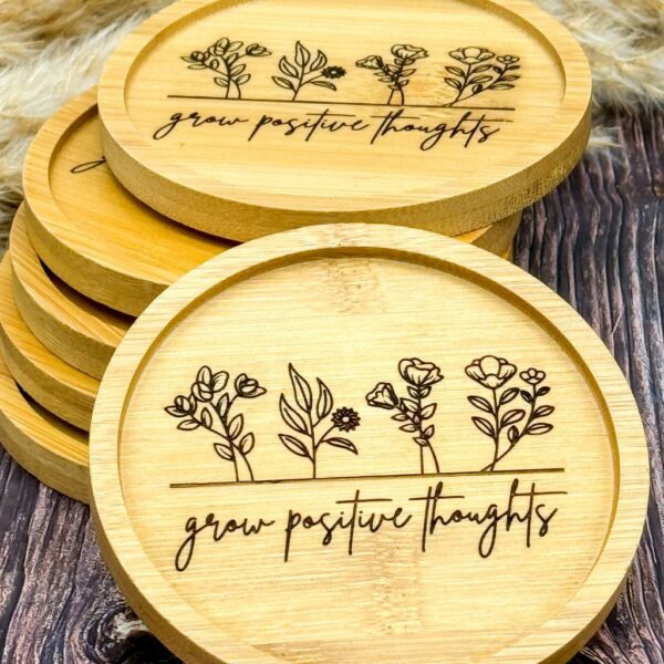 Stapel mit Bambusuntersetzer mit Lasergravur "Grow positive thoughts" und zarter Blümchen-Gravur