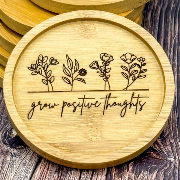 Nahaufnahme Bambusuntersetzer mit Lasergravur "Grow positive thoughts" und zarter Blümchen-Gravur