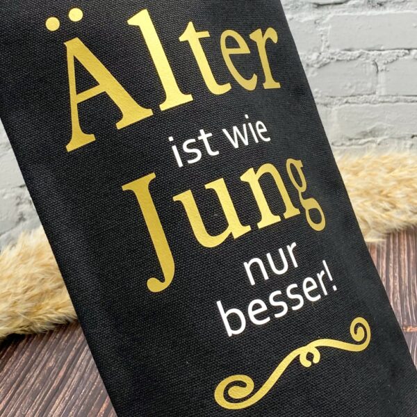 Nahaufname Flaschentasche schwarz mit Aufdruck in gold und weissem Spruch "Aelter ist wie Jung nur besser"