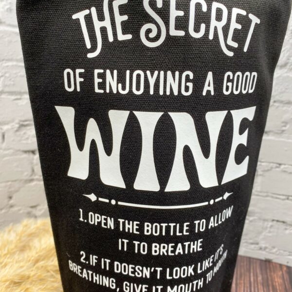 Nahaufname schwarze Flaschentasche mit lustigem Spruch "The Secret of enjoying a good wine..."