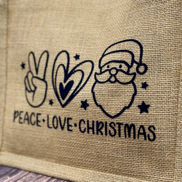 Nahaufnahme beige Jutetasche mit weissem Aufdruck "Peace - Love - Christmas" und dazugehörenden Symbolen