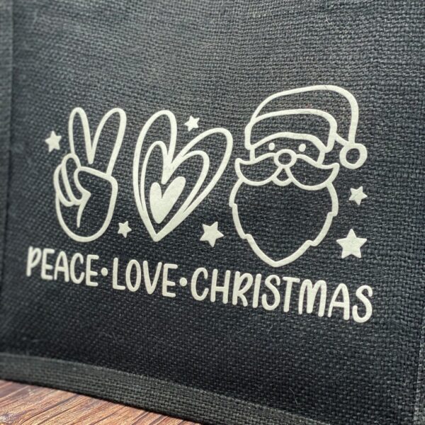 Nahaufnahme schwarze Jutetasche mit weissem Aufdruck "Peace - Love - Christmas" und dazugehörenden Symbolen