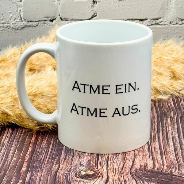 Klassische Keramiktasse mit inspirierendem Spruch „Atme ein. Atme aus.“ – ideal für Meditation und entspannte Teemomente.