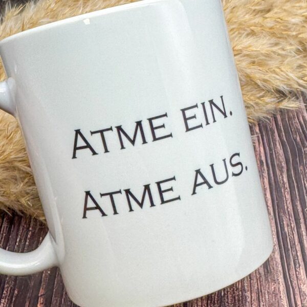 Nahaufnahme der Keramiktasse mit Spruch „Atme ein. Atme aus.“ – eine Teetasse für Achtsamkeit und Meditation.