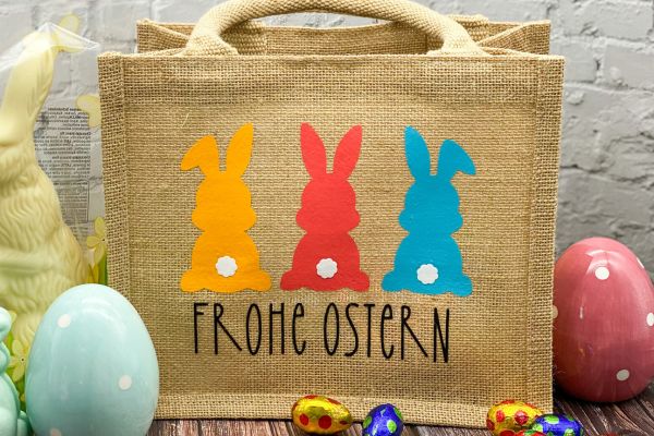 Jutetasche mit bunten Hasen bedruckt und dem Spruch "Frohe Ostern" als alternative Osternest-Idee