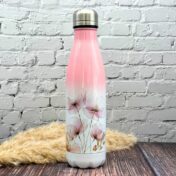 Trinkflasche aus Edelstahl mit Blütenmotiv, stehend auf Holzuntergrund