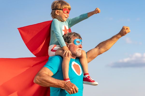 Väter sind Helden - Vater mit Sohn auf seiner mit Superheldenanzügen & -pose